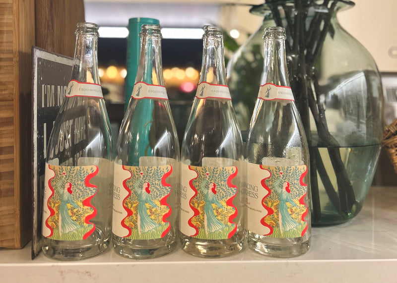 Vintage bottles with decorative labels on a shelf with a plant in the background
